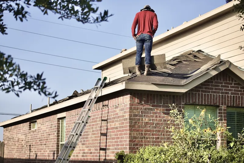 Professional roofer working on a residential roof in Champlain